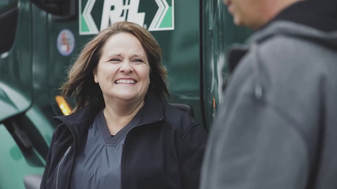 Woman smiling in front of R+L Carriers truck